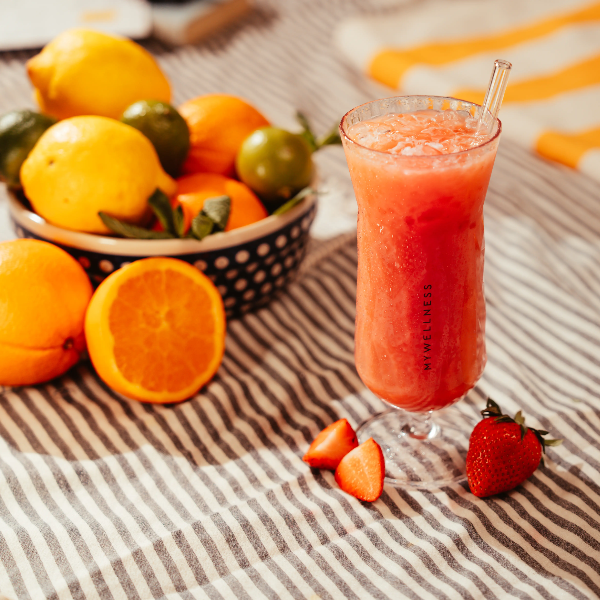 Erfrischender Erdbeer-Smoothie im MyWellness-Glas neben einer Schale mit frischen Zitrusfrüchten