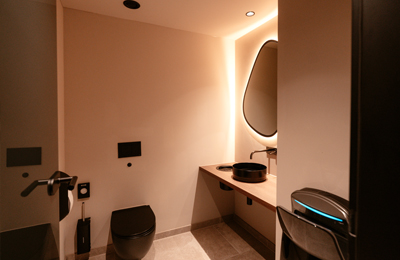 Modernes Badezimmer mit schwarzen Sanitärelementen und Spiegelbeleuchtung in der MyWellness Suite