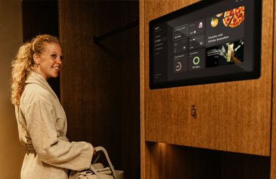 Frau im Bademantel bedient das Touchpanel zur Bestellung von Snacks und Drinks in der MyWellness Suite